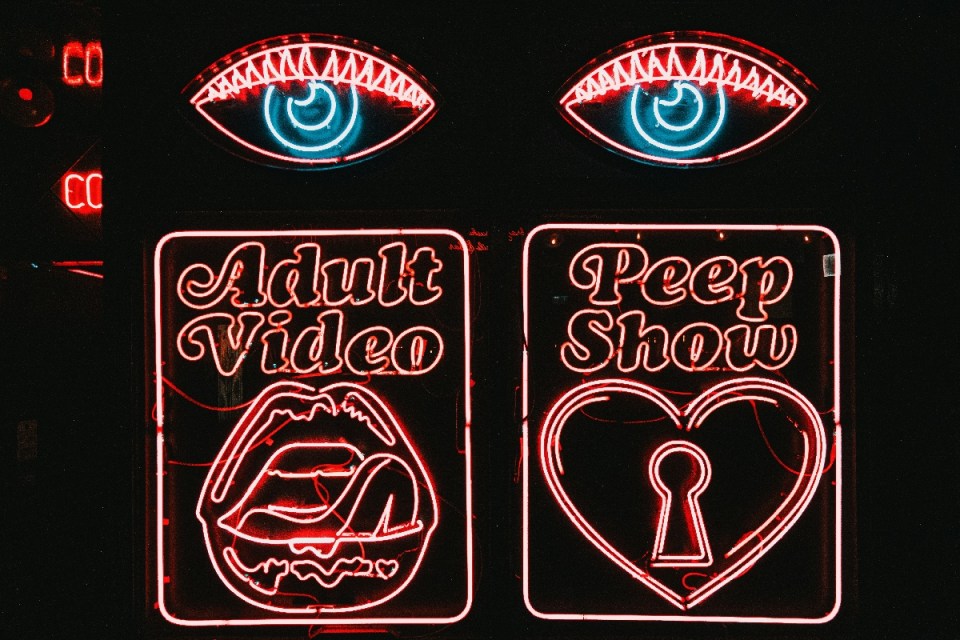 Red neon Adult Video and Peep Show signs with eyes, lips, and heart.