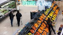 Overhead view of shoppers in a grocery stores fruit and vegetable aisle under a Fruit & Veg sign