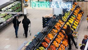 Overhead view of shoppers in a grocery stores fruit and vegetable aisle under a Fruit & Veg sign