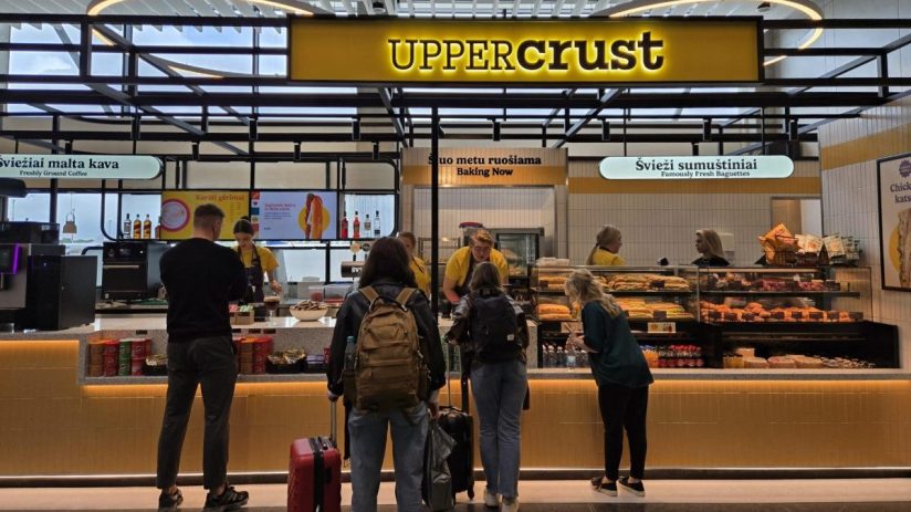 Upper Crust bakery and cafe at Vilnius Airport, with customers ordering fresh baguettes and coffee.