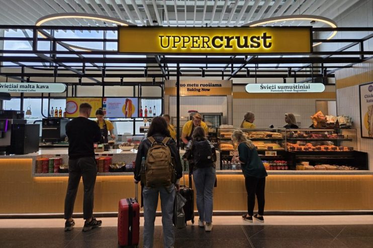 Upper Crust bakery and cafe at Vilnius Airport, with customers ordering fresh baguettes and coffee.