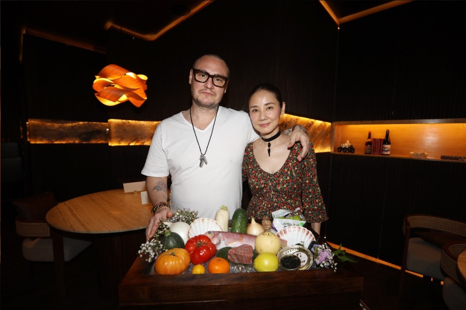 Victor and Yoh with a display of fresh produce, fish, and caviar in a restaurant setting.