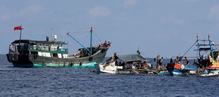 FILE PHOTO: A Chinese fishing vessel is anchored next to Filipino fishing boats at Scarborough Shoal